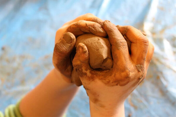 Decje ruke stiskaju glinu
