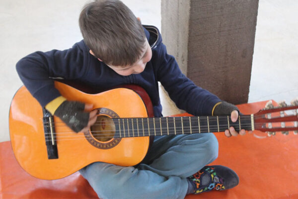 Decak svira gitaru u sedecem polozaju