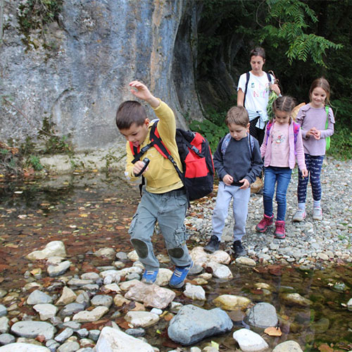 Deca preskacu preko kamenja u potoku
