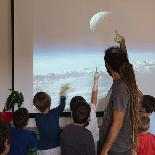 Deca i nastavnik pokazuju ka projektnom platnu
