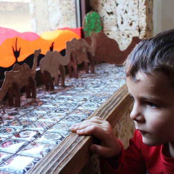 Dete radoznalo posmatra modele kamila od balze na podprozorniku
