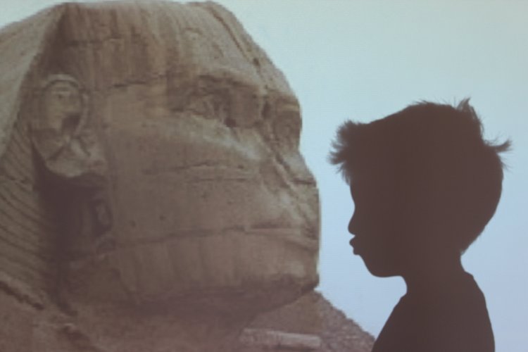 Senka profila deteta ispreed projektnom platna na kome je prikazana Sfinga